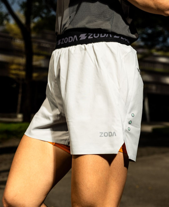 Person wearing white athletic shorts with 'Zoda' branding outdoors. Zoda Pulse Collection
